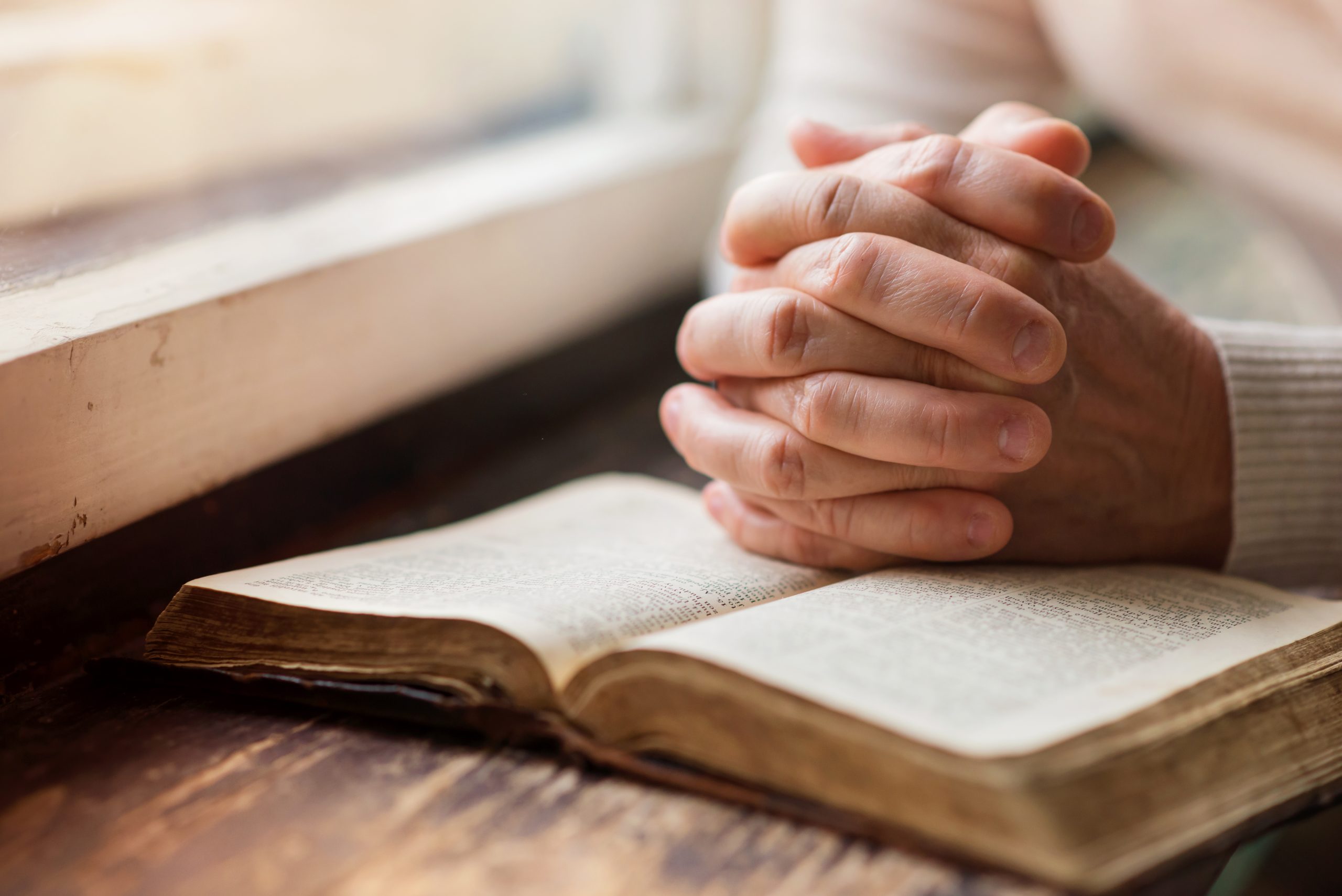 Unrecognizable woman holding a bible in her hands and praying